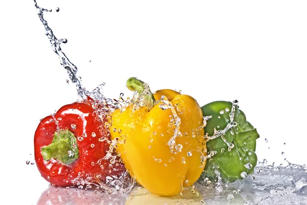 Červené, žluté a zelené papriky s stříkající vodě — Stock fotografie