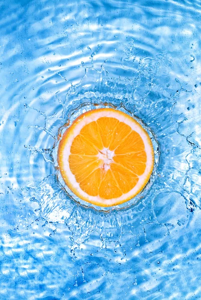 Свіжий апельсин впав у воду з бульбашками — стокове фото