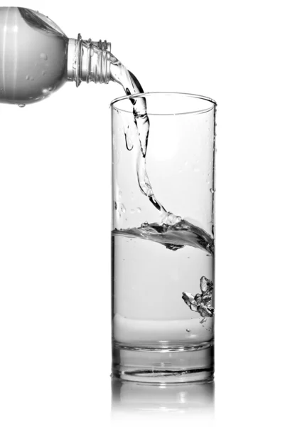 Вода из бутылки льется в стекло — стоковое фото