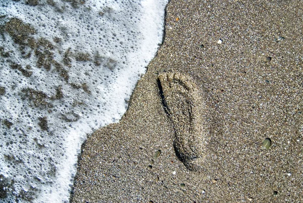 Песчаные камни с отпечатками обуви и волнами воды — стоковое фото