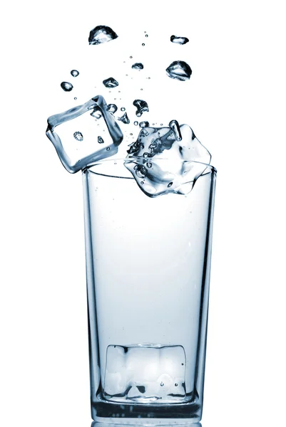 Ледяные кубики падают в стекло с пузырьками — стоковое фото