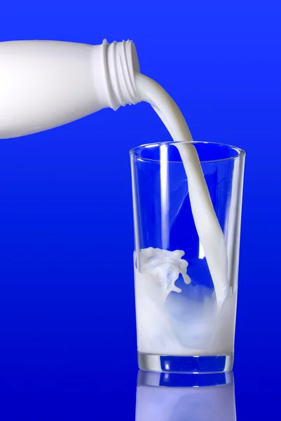 Milk pouring from bottle into glass — Stock Photo, Image