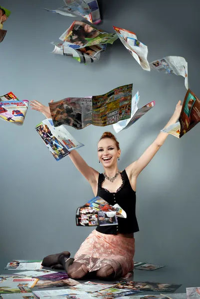 Усміхнена дівчина викидає журнали — стокове фото