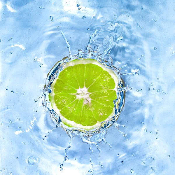 Verse limoen gedaald in water met bubbels geïsoleerd op wit — Stockfoto