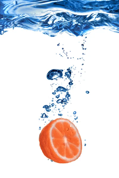 Färsk grapefrukt tappade i vatten med bubblor isolerad på vit — Stockfoto