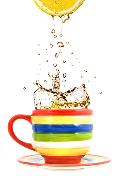 Limão, xícara de cor e respingo de chá isolado no branco — Fotografia de Stock