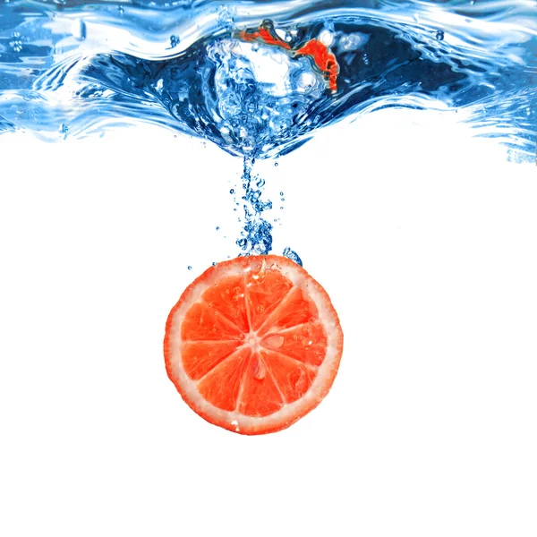 Färsk grapefrukt tappade i vatten med bubblor isolerad på vit — Stockfoto