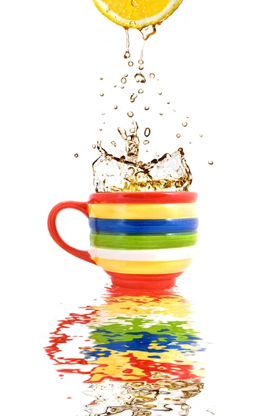 Jus de citron et éclaboussures de thé en tasse de couleur avec réflexion — Photo