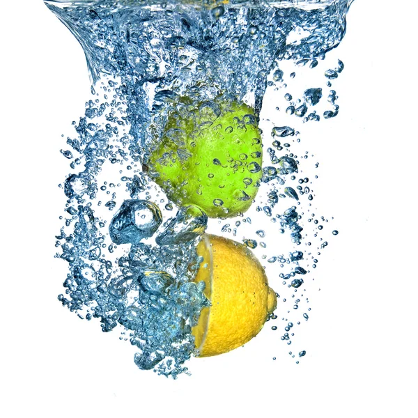 Citronu a limetky vhozeni do vody s bublinkami izolovaných na bílém — Stock fotografie