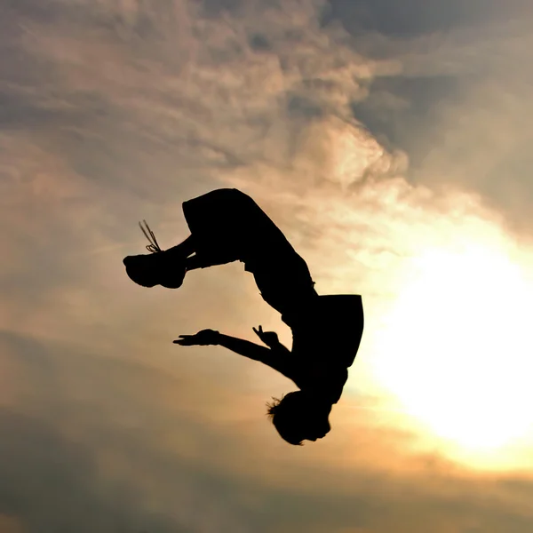 Silhueta de homem de salto contra céu e nuvens — Fotografia de Stock