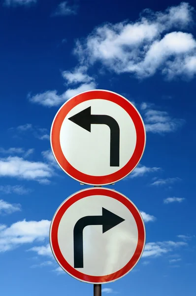 Dois sinais de estrada opostos contra céu azul e nuvens — Fotografia de Stock