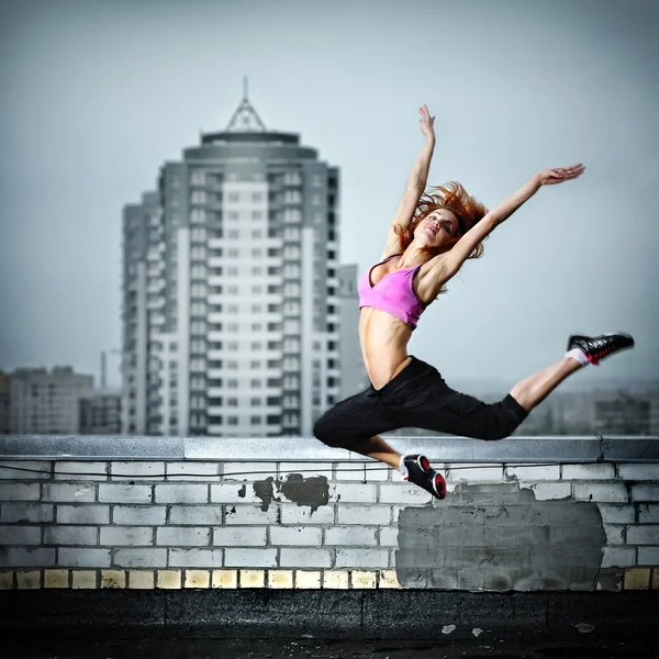 Girl posing on the roof against city background — Stock Photo, Image