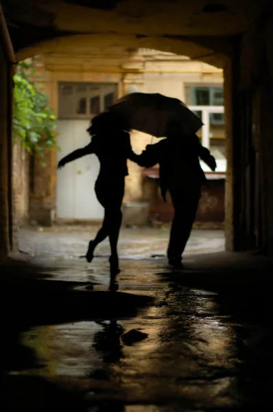 Silhueta de casal com guarda-chuva correndo da chuva — Fotografia de Stock