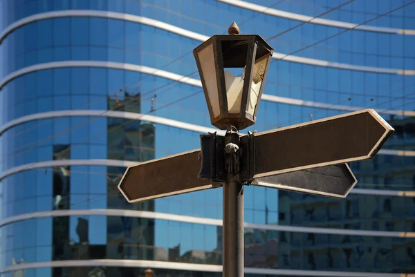 Lege wegwijzer met oude lamp tegen zakelijke gebouw — Stockfoto