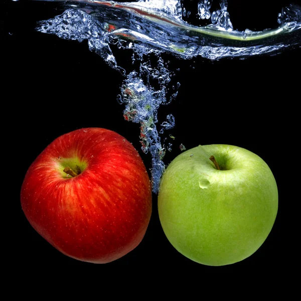 Manzanas arrojadas al agua con salpicaduras aisladas en negro —  Fotos de Stock