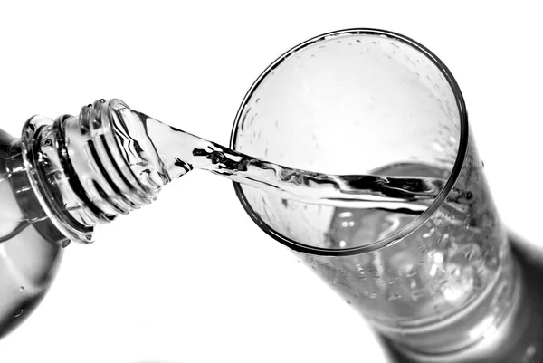 Acqua versata in vetro da bottiglia isolata su bianco — Foto Stock