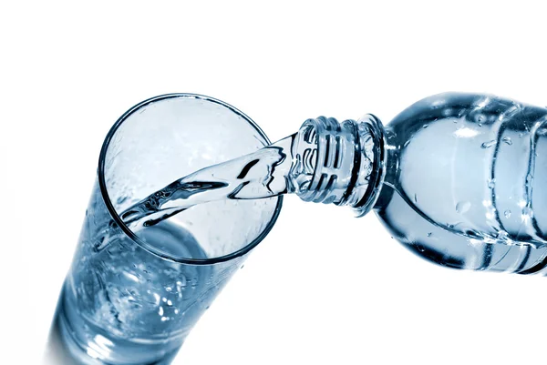 Water gieten in glas van fles geïsoleerd op wit — Stockfoto