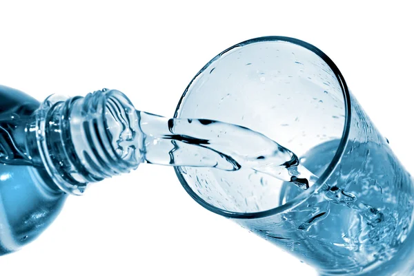 Água que despeja no vidro da garrafa isolada no branco — Fotografia de Stock
