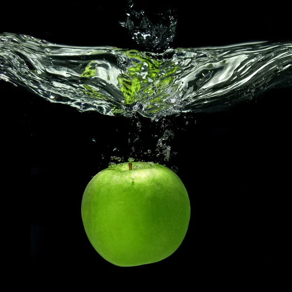 Maçã verde caiu na água com respingo isolado em preto — Fotografia de Stock