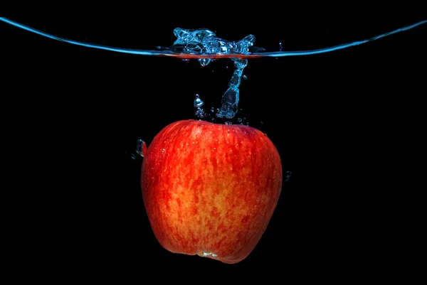 Rött äpple föll i vattnet med stänk isolerade på svart — Stockfoto