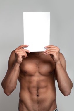 Muscular naked man holding white empty paper clipart