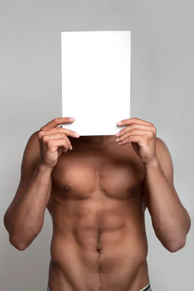Muskulös naken man som håller vitt tomt papper — Stockfoto