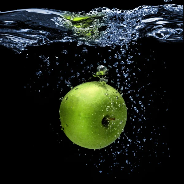 青苹果掉入水中与飞溅孤立在黑色 — 图库照片