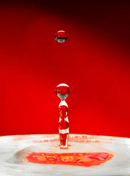 Vallende druppels water over rood — Stockfoto