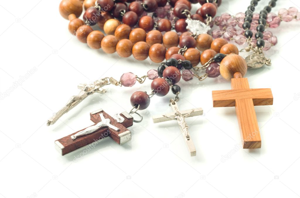 Rosary beads over white with focus on crosses