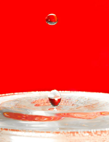 Vallende druppels water over rood — Stockfoto