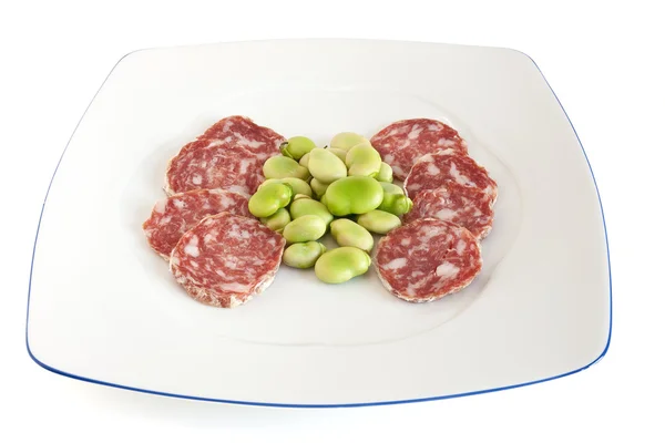 Dish with fava beans and salami slices — Stock Photo, Image