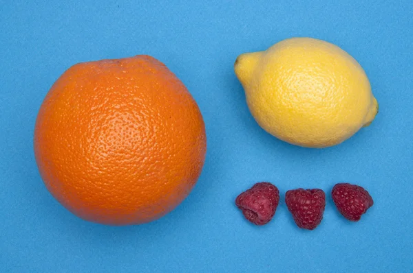 Apelsin, citron och hallon på blå — Stockfoto
