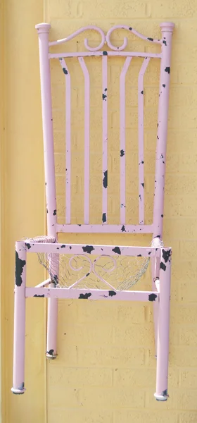 Розовый стул на жёлтой стене — стоковое фото
