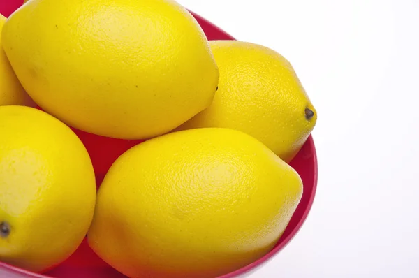 Leuchtend gelbe Zitronen in einer rosa Schüssel — Stockfoto