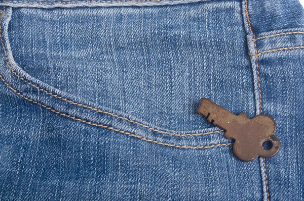 Антикварный ключ в джинсовых синих штанах — стоковое фото