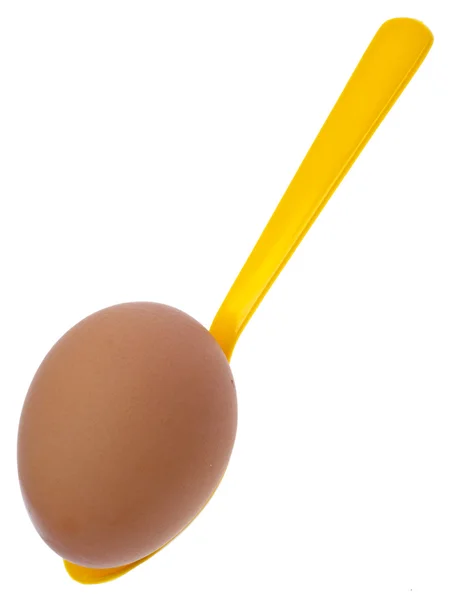 Желтая ложка с коричневым яйцом — стоковое фото