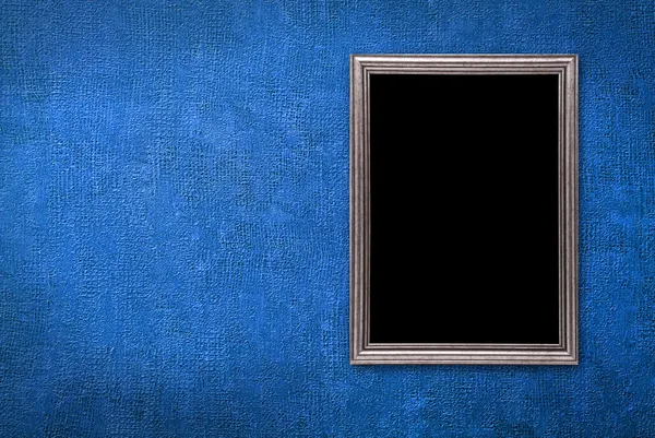 Серебряная рамка на фоне синей стены — стоковое фото