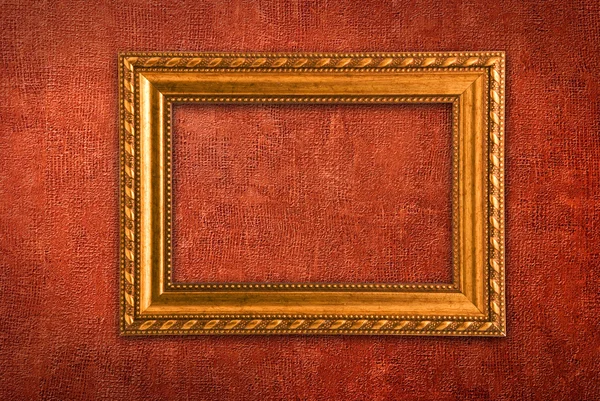 Gold frame on a red wall background — Stock Photo, Image