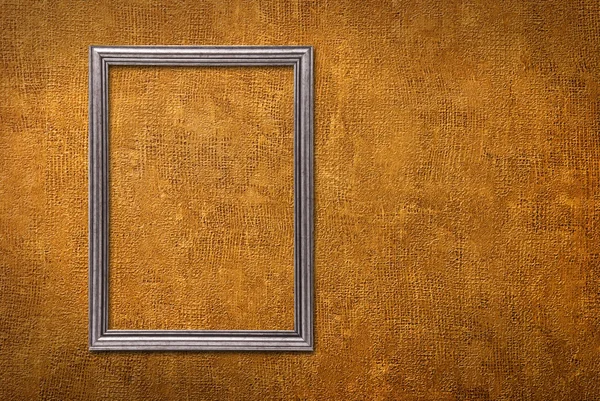 Серебряная рамка на фоне желтой стены — стоковое фото