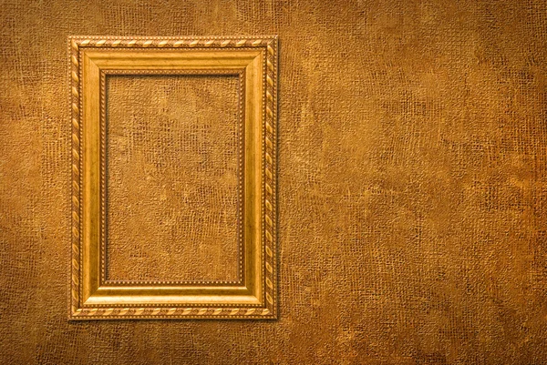 Moldura de ouro em um fundo de parede amarelo — Fotografia de Stock