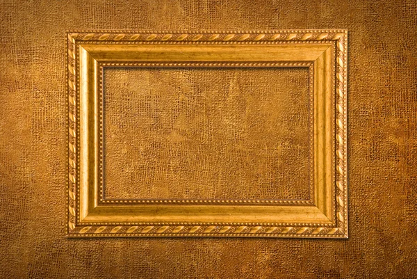 Золотая рамка на фоне желтой стены — стоковое фото