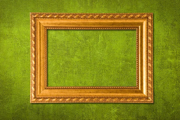 Moldura de ouro em um fundo de parede verde — Fotografia de Stock