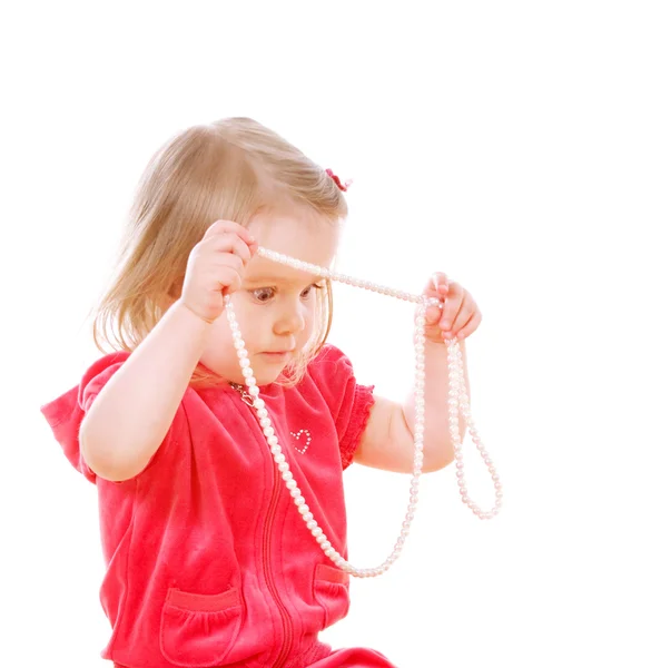 Little serious girl holds a pearl necklace — Stock Photo, Image