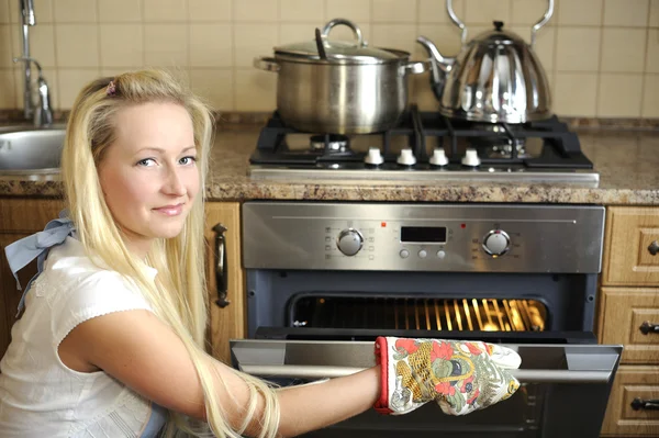 Prachtige huisvrouw schakelen de oven — Stockfoto