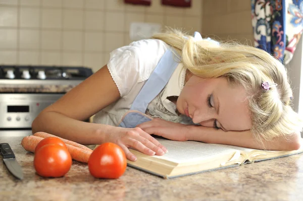 Jeune femme au foyer dormir sur le livre de cuisine Images De Stock Libres De Droits