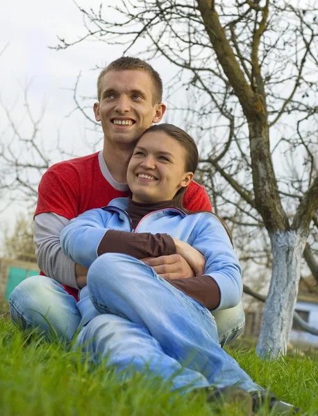 Молодая пара, сидящая на траве — стоковое фото