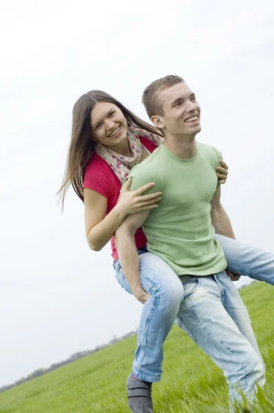 Молодая пара играет на зеленом поле — стоковое фото