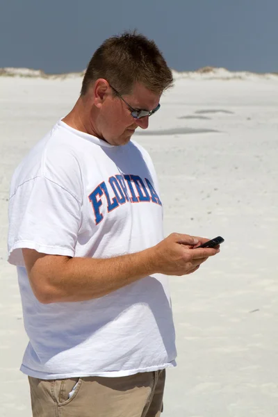 Man texting op strand — Stockfoto