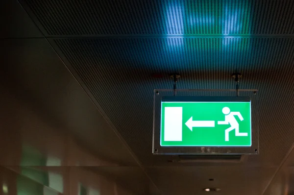Illuminated green emergency exit sign — Stock Photo, Image
