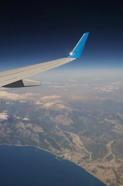 Airplane under mountains and sea — Stock Photo, Image